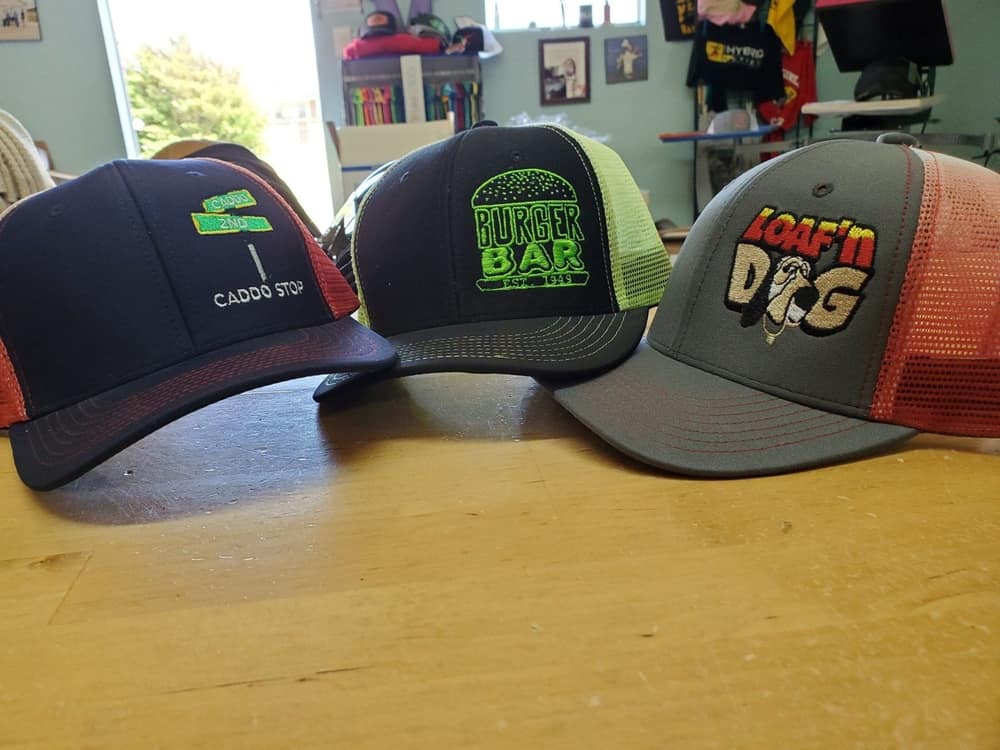 Three embroidered trucker caps in blue, black and grey with contrast logos.